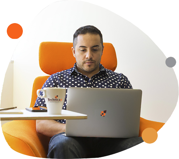 Man working on a laptop at a desk in a modern office setting.